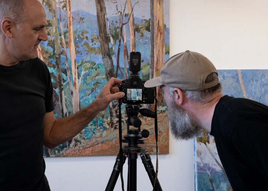 Adam Pyett inspecting artwork through the camera lens.